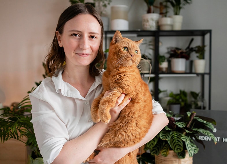 Vrouw houdt een rode kat vast in huis – huisdier helpt tegen eenzaamheid